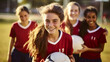 © Sam - Teenager girls soccer team smiling wearing red kit and holding a ball on soccer field school sport physical activity fitness