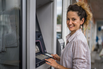 woman using credit card and withdrawing cash at the ATM