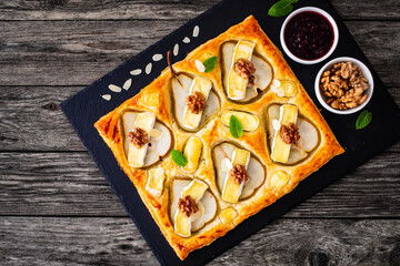 Poster - Baked puff pastry with pear and camembert cheese on baking paper on wooden table
