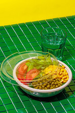 Salad Bowl On Green Background With Plastic Cover Near Glass Of Water
