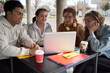 © CarlosBarquero - Group of students sharing a laptop to do homework. They are sitting outside in a bar table in the campus.