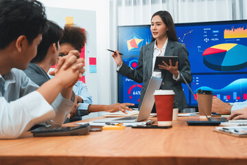 Young asian businesswoman presenting data analysis dashboard on TV screen in modern meeting. Business presentation with group of business people in conference room. Concord