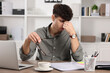 © New Africa - Tired young man working at table in office. Deadline concept
