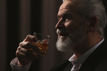 Poster - Senior man in suit drinking whiskey on brown background