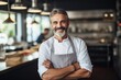 © Baba Images - Middle aged australian caucasian chef working in a restaurant kitchen smiling portrait