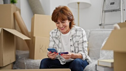 Poster - Middle age woman shopping with smartphone and credit card at new home