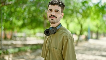 Poster - Young hispanic man smiling confident wearing headphones at park