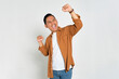 Big win. Excited young Asian man in casual shirt celebrating success with raised fist isolated on white background