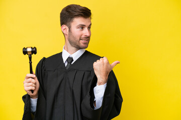 Wall Mural - Judge caucasian man isolated on yellow background pointing to the side to present a product