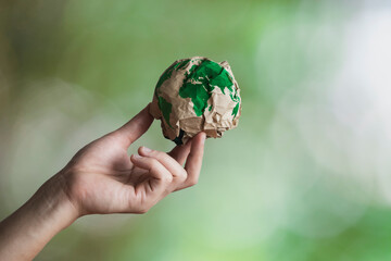 Wall Mural - sustainable environmental concept. Human hand holding recycled paper globe.