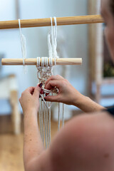 Wall Mural - Young woman weaving with white macrame.