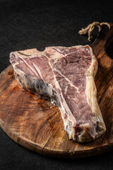 Wall Mural - Siroy piece of beef meat T-bone, lies on a wooden board with spices. place for text, photon image. top view