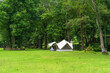 nature landscape camping or white glamping cabin tent on green grass lawn campground and tree for camper family holiday vacation on rainy season at khao laem national park in ka teng cheng waterfall