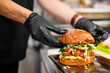 © pavel siamionov - chef hand cooking cheese burger with vegetables and meat on restaurant kitchen