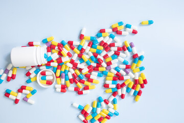 Wall Mural - Group of assorted color tablets. Pills spilling out of white bottle on blue background. Top view with copy space for text.