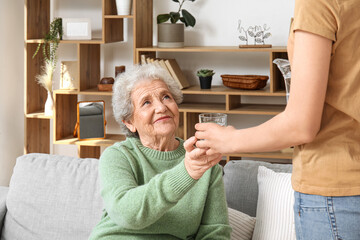 Poster - Senior woman taking glass of water from her granddaughter at home