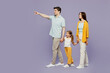 © ViDi Studio - Full body side view young parents mom dad child kid daughter girl 6 years old wearing blue yellow casual clothes hold hands walk go point aside isolated on plain purple background. Family day concept.