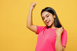 Young overjoyed fun happy Indian woman wear pink t-shirt casual clothes doing winner gesture celebrate clenching fists say yes isolated on plain yellow background studio portrait. Lifestyle concept