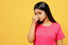 Young Sick Ill Sad Thoughtful Tired Indian Woman Wearing Pink T-shirt Casual Clothes Keep Eyes Closed Rub Put Hand On Nose Think Isolated On Plain Yellow Background Studio Portrait. Lifestyle Concept.