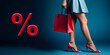 elegant slender legs of a young woman with a red handbag on a blue background. the concept of shopping and discounts