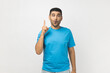 © khosrork - Portrait of excited amazed clever smart unshaven man wearing blue T- shirt standing with finger up, having idea, looking at camera with surprised face. Indoor studio shot isolated on gray background.