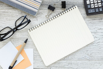 Wall Mural - An open notebook with blank pages, a pen and a calculator on a wooden table. view from above