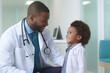 © SnapVault - A young child wearing a white coat who aspires to become a doctor receives motivation from an African American physician at the hospital