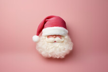 Minimalistic Christmas Composition Featuring The Head Of A Santa Claus Doll Against A Pink Gradient Background. Santa's Red Hat Is Covering The Doll's Eyes.