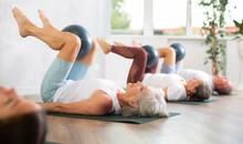 Active Senior Women Doing Pilates With Soft Ball Lying On Back In Gym