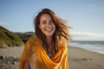 Sticker - Portrait of a smiling young woman with yellow scarf on the beach