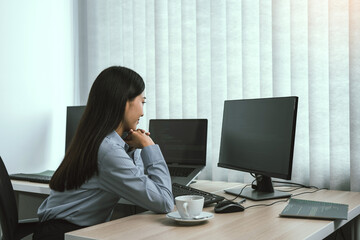 Wall Mural - asian woman software developers sitting in front of computers looking at computer codes on the scree