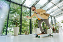 Cheerful Businessman Enjoying Longboard Skating In Office