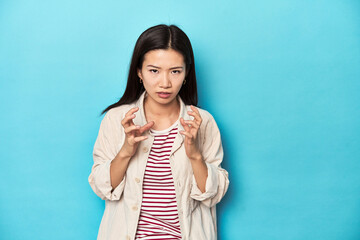 Wall Mural - Asian woman in layered shirt and striped t-shirt, upset screaming with tense hands.