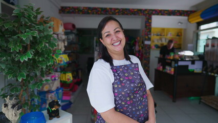 Wall Mural - Happy female worker wearing apron smiling at camera in front of local Small Business Storefront