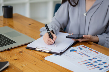 Female accountant analyzing charts, graphs, computer, investment tablet and pressing calculator button above document. Accountants, accountants, clerks, bank consultants and auditors. close-up photo