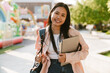 © Drobot Dean - Asian woman with backpack and laptop smiling at camera while standing outdoors