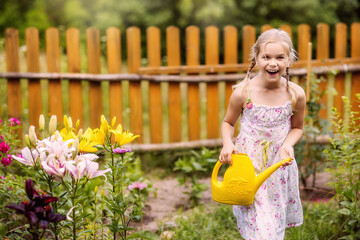 Wall Mural - a girl with a watering can watering flowers, cheerful, laughing, summer, garden, vegetable garden, village