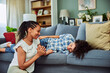 © bnenin - A smiling African woman is on the floor talking with her son while he lying on a couch.