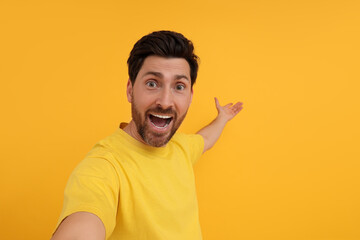 Poster - Happy man taking selfie on yellow background, space for text