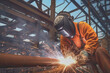 A welding specialist with sparks flying from the welding torch while working to construct a metal structure.