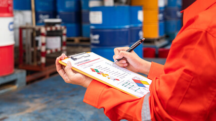 Wall Mural - a worker is checking on the hazardous chemical material information form with background of chemical
