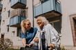 © Maskot - Smiling female caregiver helping happy senior woman walking outside building
