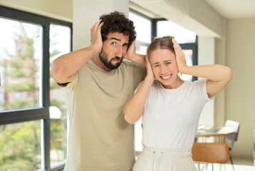 Wall Mural - young adult couple feeling stressed, worried, anxious or scared, with hands on head, panicking at mistake