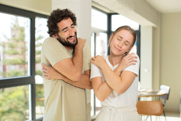 Canvas Print - young adult couple feeling in love, smiling, cuddling and hugging self, staying single, being selfish and egocentric