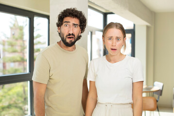 Canvas Print - young adult couple feeling terrified and shocked, with mouth wide open in surprise