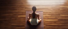 Top Down View Of A Young Woman Doing Yoga Indoors Sitting In A Relaxed Posture On A Wooden Floor Meditating And Finding Inner Peace Creating Copy Space