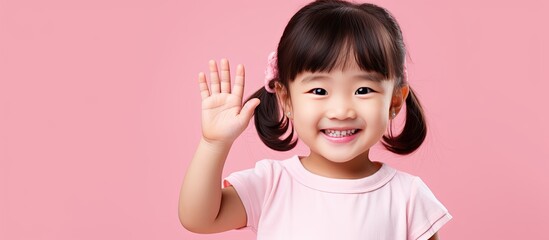 Poster - Joyful Asian girl displaying open palm with copy space on a pink background