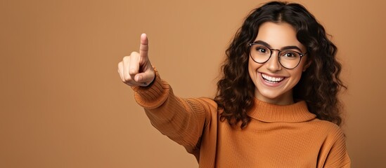 Poster - Smiling young woman happily points upwards to show an object