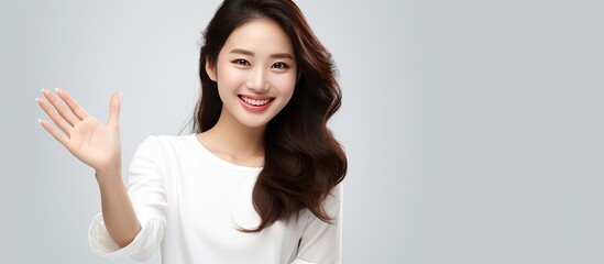 Poster - Attractive Asian woman in white shirt smiling with open hands on white background looking for copy space