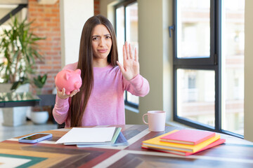 Poster - looking serious showing open palm making stop gesture. piggy bank concept